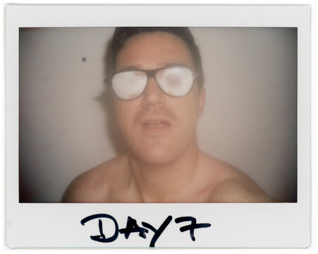 Man With Moustache Taking Instant Pictures in a Simple Setting