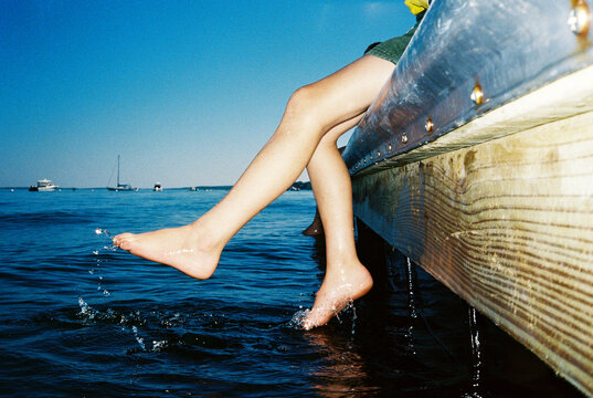 Child splashing feet in water off dock