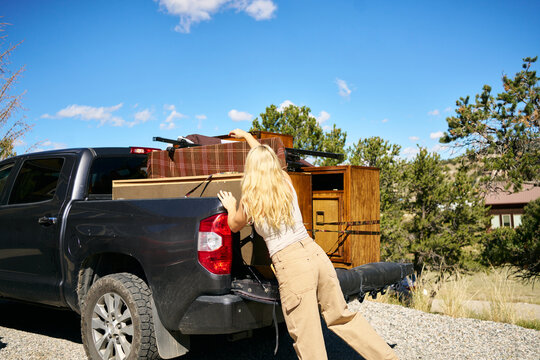 Woman loading vintage furniture into pickup truck