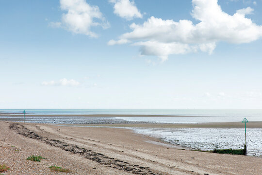 Calm Low Tide Beach With Mudflats, Sea Horizon And Cloudy Sky At Coastal Shore
