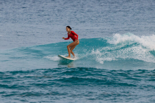 Woman surfer in swimsuit on wave in tropical ocean