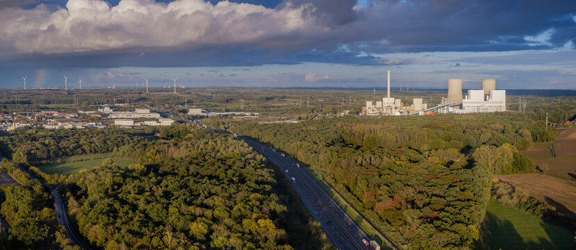 Aerial view of a busy A2 highway with moving traffic, featuring industrial chimneys and cooling towers of a coal-fired power station in the background.