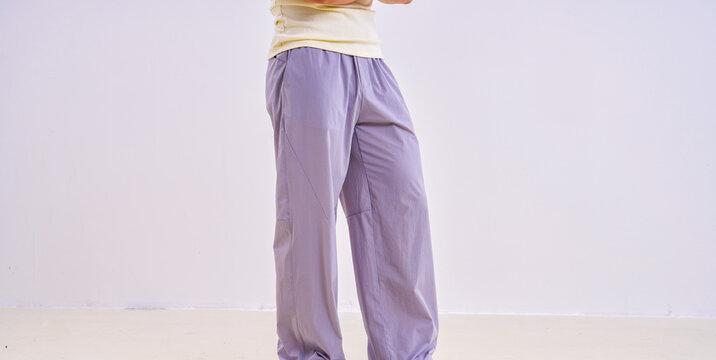                               Asian athletic male model in light purple loose casual trousers, studio apparel photo on plain background 