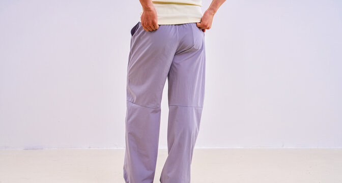                               Asian athletic male model in light purple loose casual trousers, studio apparel photo on plain background 