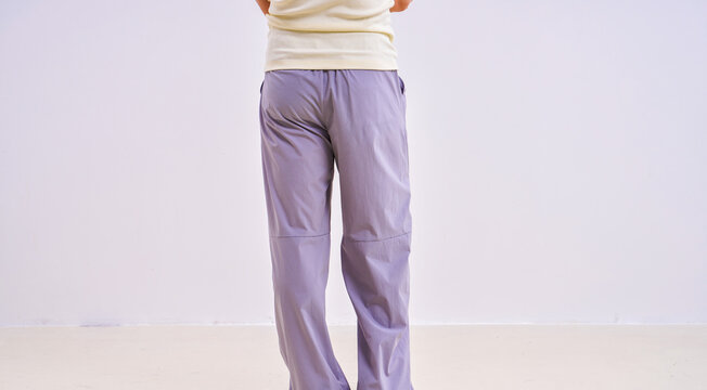                               Asian athletic male model in light purple loose casual trousers, studio apparel photo on plain background 