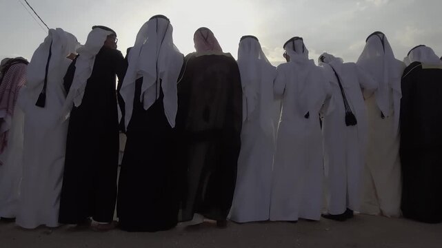 Row of Arab men in traditional robes standing together at dusk in southern Iraq