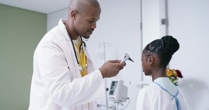 Male clinician in lab coat inserting otoscope, inspecting teen girl ear in clinic then high-fiving