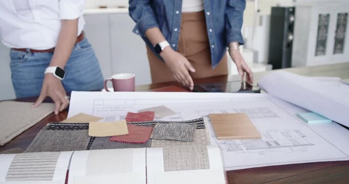 Indian women starting review arranging swatches on studio desk using tablet matching elevations