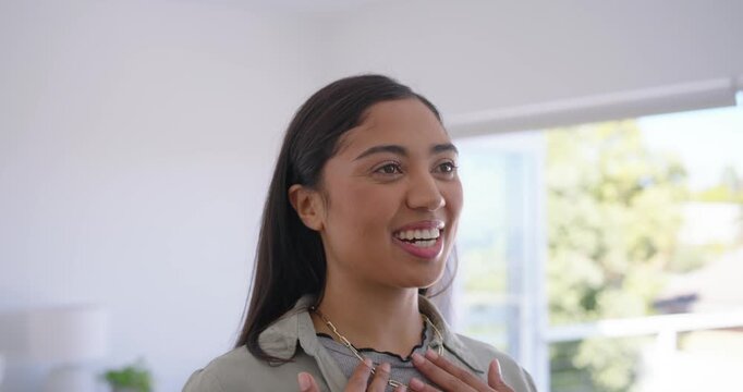 Woman smiling, tucking hair, adjusting layered necklaces in living room responding offscreen