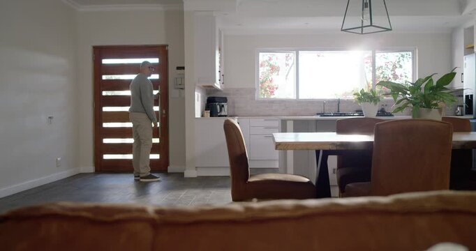 Mature African man entering door at home checking panel placing specs on table sitting holding head