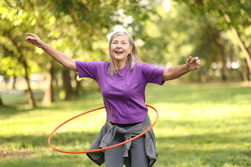 Senior woman exercising with hula hoop outdoors © New Africa