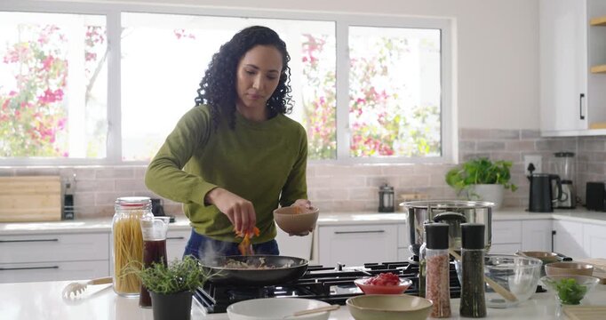 African American woman entering kitchen adding grated cheese to pan stirring with spatula cooking