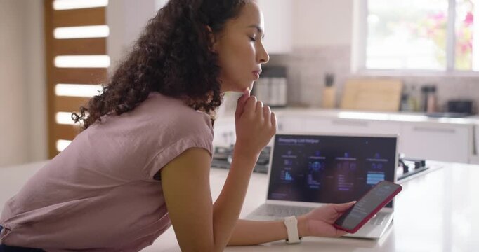 African American woman at kitchen island viewing Shopping List Helper on laptop, updating red phone