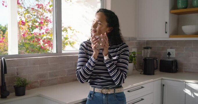 African American woman holding mug, sipping, looking out kitchen window, sunlight urging pause