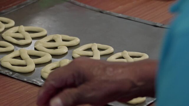 Baker arranging rosquete dough on baking tray in mexican bakery
