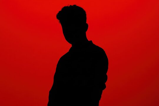 silhouette of a person standing against a vibrant red background