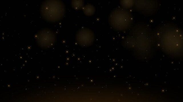 Golden dust particles floating on black background with soft bokeh