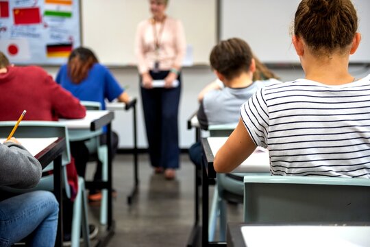 Students taking a classroom test while a female teacher supervises
