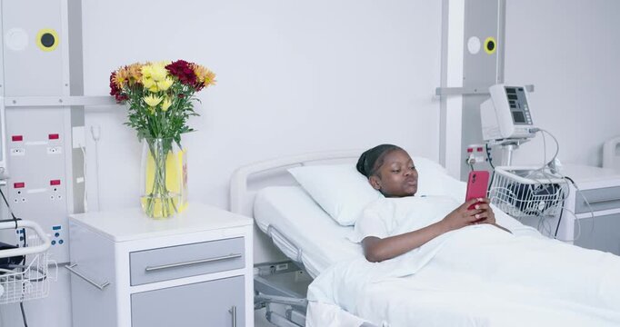 African American youth lying in hospital bed, scrolling red phone seeing meme, smiling, copy space