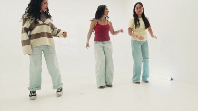 Three young women dancing in bright white studio
