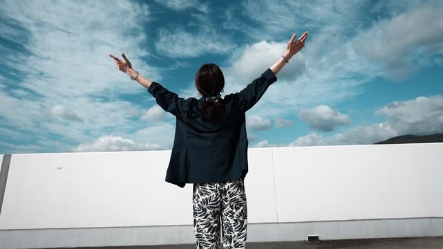 Person Raising Arms Toward Blue Sky in Celebration and Freedom, Slow Motion