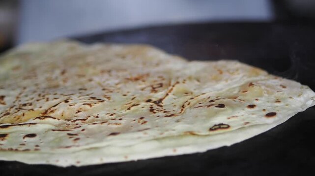 Flatbread cooks on a hot surface in a close-up view