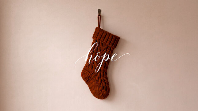 minimal graphic composition of a single knit christmas stocking hanging in deep crimson with the word hope overlaid in elegant cursive text against a warm subtle beige backdrop