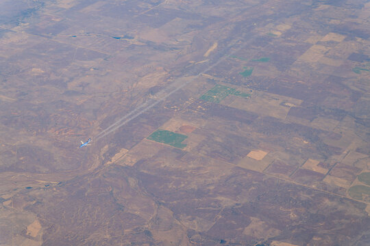 Aerial view of airplane flying over patchwork farmland and terrain in