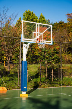 맑고 푸른 하늘 아래 공원에 위치한 빈 야외 농구장(Empty outdoor basketball court in a park under clear blue sky in Korea.)