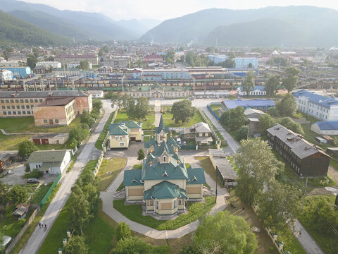 Aerial view of St. Nicholas Orthodox church with green roofs and railway station in Slyudyanka, Irkutsk Oblast, Russia