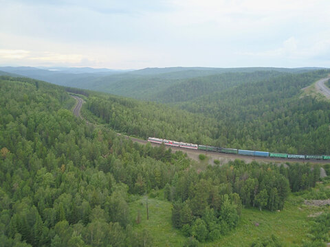 Trans-Siberian Railway: Freight train on double-track railway climbing a hill in forested hills near Kultuk, Irkutsk Oblast, Russia