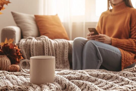 Cozy Autumn Living Room with Warm Textures and Natural Light . A comfortable living space with a knitted blanket, ceramic mug, and warm seasonal tones. woman in cosy clothes 