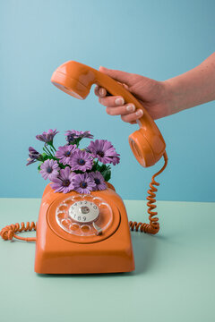 Hand holding receiver of retro telephone, concept of summer calling