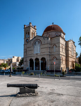 
Church of Panagitsa (The Presentation of the Virgin) features local limestone architecture, a prominent dome, and a bell tower, with a historic cannon displayed in the foreground plaza. Aegina, Greec