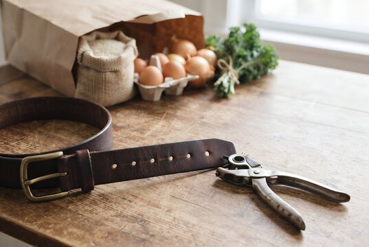 Leather belt with a freshly punched extra hole beside groceries