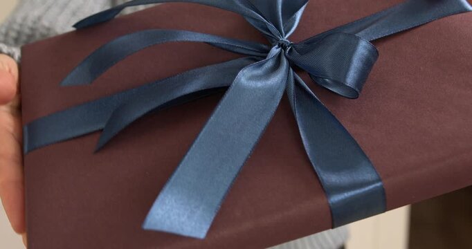 Woman hands holding and showing gift box with blue satin ribbon close up video