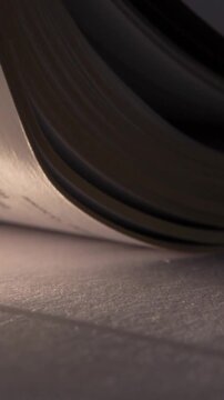 Vertical video: Cam shifting pages curling showing cross pendant sliding into warm light for focus