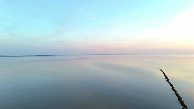 Calm sunset over the mudflats of the North Sea, Schleswig-Holstein, Germany, Europe. Sunset colors reflecting on calm shallow water over North Frisia mudflats during low tide, North Frisia, Germany, E