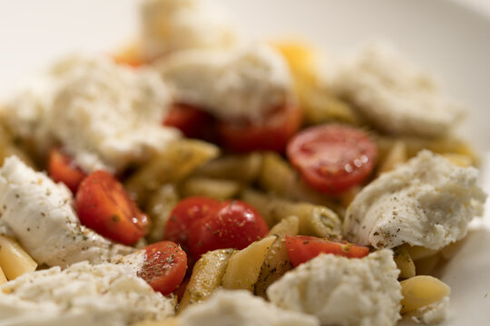 Penne pasta with mozzarella, pesto and fresh cherry tomatoes
