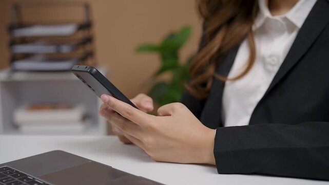 Businesswoman using smartphone in modern office environment for communication or digital multitasking concept