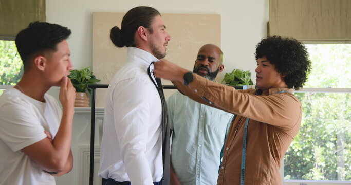 Groom getting ready as friend helps adjust collar, smiling in preparation