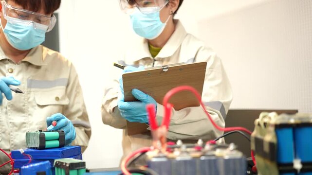 The skilled technician works on the lithium phosphate battery circuit board with his partner.