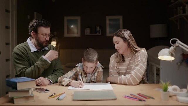 Father and mother watch child doing homework at home in evening. Parents supervise child completing homework. Parenting supervision education family concept