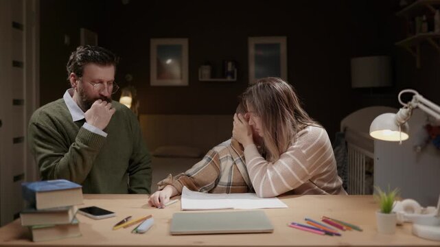 Father and mother hug upset child while doing homework at home. Parents support distressed son. Emotional support parenting comfort family concept
