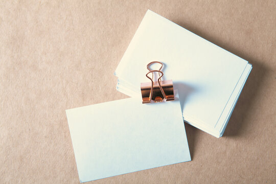 Blank business card and binder clip on vintage paper background.