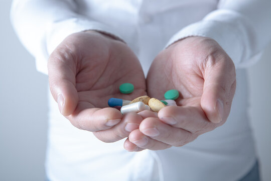 Man holding pills in his hand. Focus on foreground, soft bokeh.