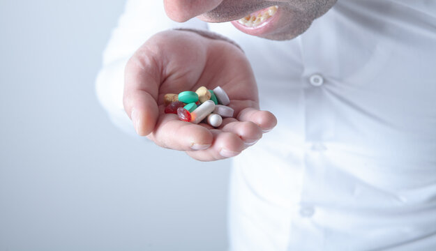 Man holding pills in his hand. Focus on foreground, soft bokeh.