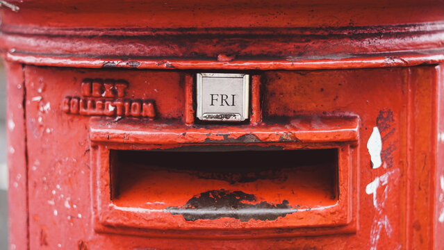Close-up of red pillar post box slot with next collection time display tab