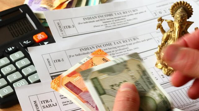 India tax return. An Indian tax return form and someone calculating Indian rupees using a calculator. Financial and business concept. Close-up.
