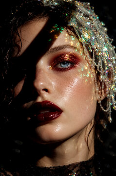Woman with blue eyes wearing sparkling sequin headpiece and dark red lipstick